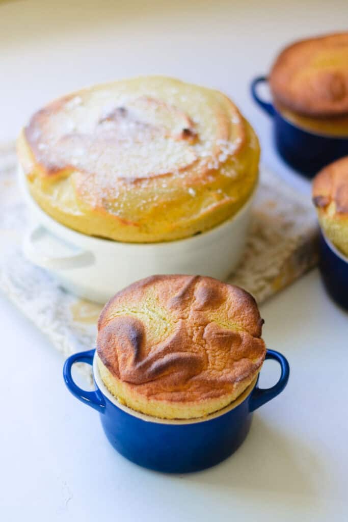 A large 6 cup pumpkin souffle is dusted with powdered sugar and small 1 cup pumpkin souffle.