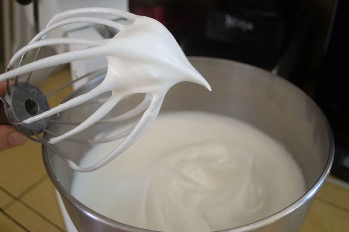 Stiff egg whites are beaten in an electric mixer with whisk attachment.