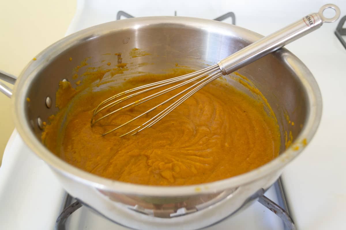 Whisk in the pumpkin puree into the milk and spices mixture to make the base of the pumpkin souffle.
