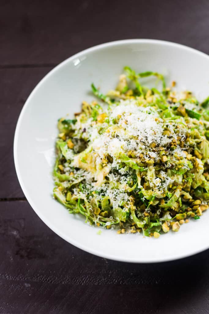 Shaved brussels sprouts salad with grated parmesan on top and chopped pistachios.