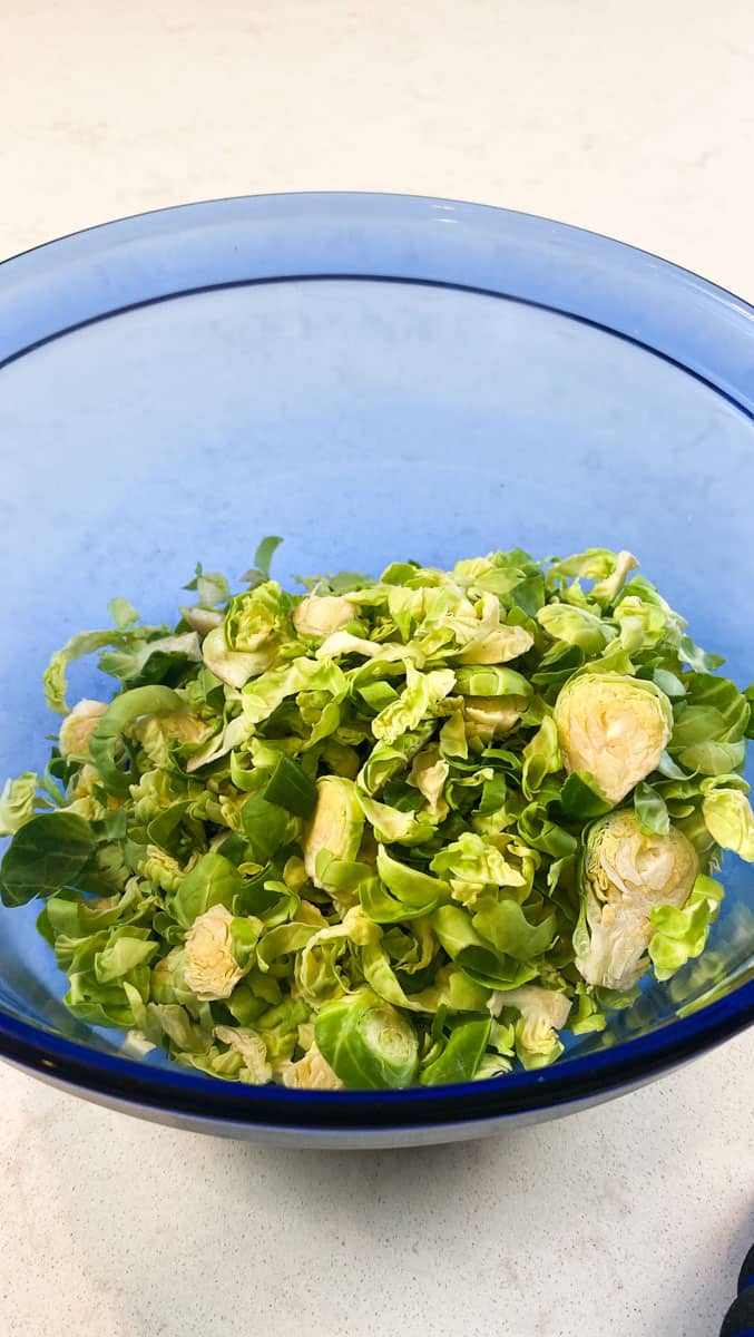 Add shredded brussels sprouts to a large salad bowl.