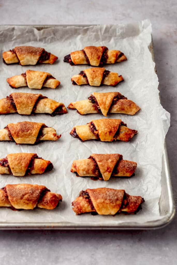 Baked cherry pistachio rugelach are on a cookie sheet.