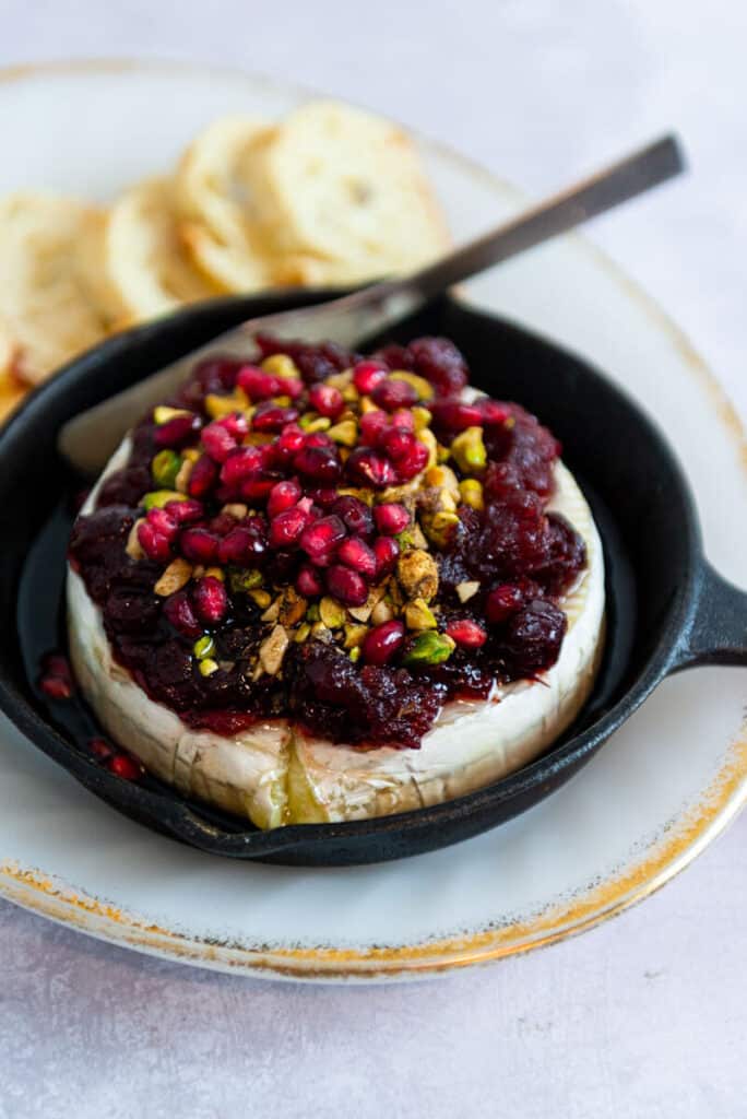 Cranberry Baked Brie topped with pistachios and pomegranate seeds.