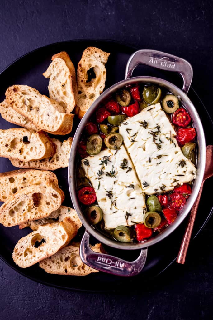 Bake feta in olive oil with cherry tomatoes and olives and serve with slices of crostini.