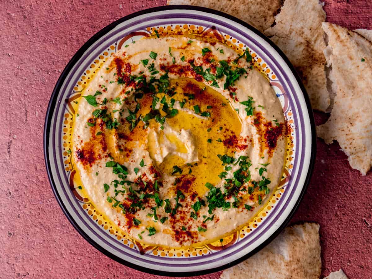 Easy and creamy homemade hummus is garnished with olive oil and sprinkle of paprika on top.