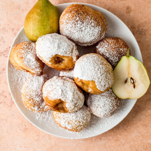 Small donuts are filled with sweet cooked pears and dusted with powdered sugar.