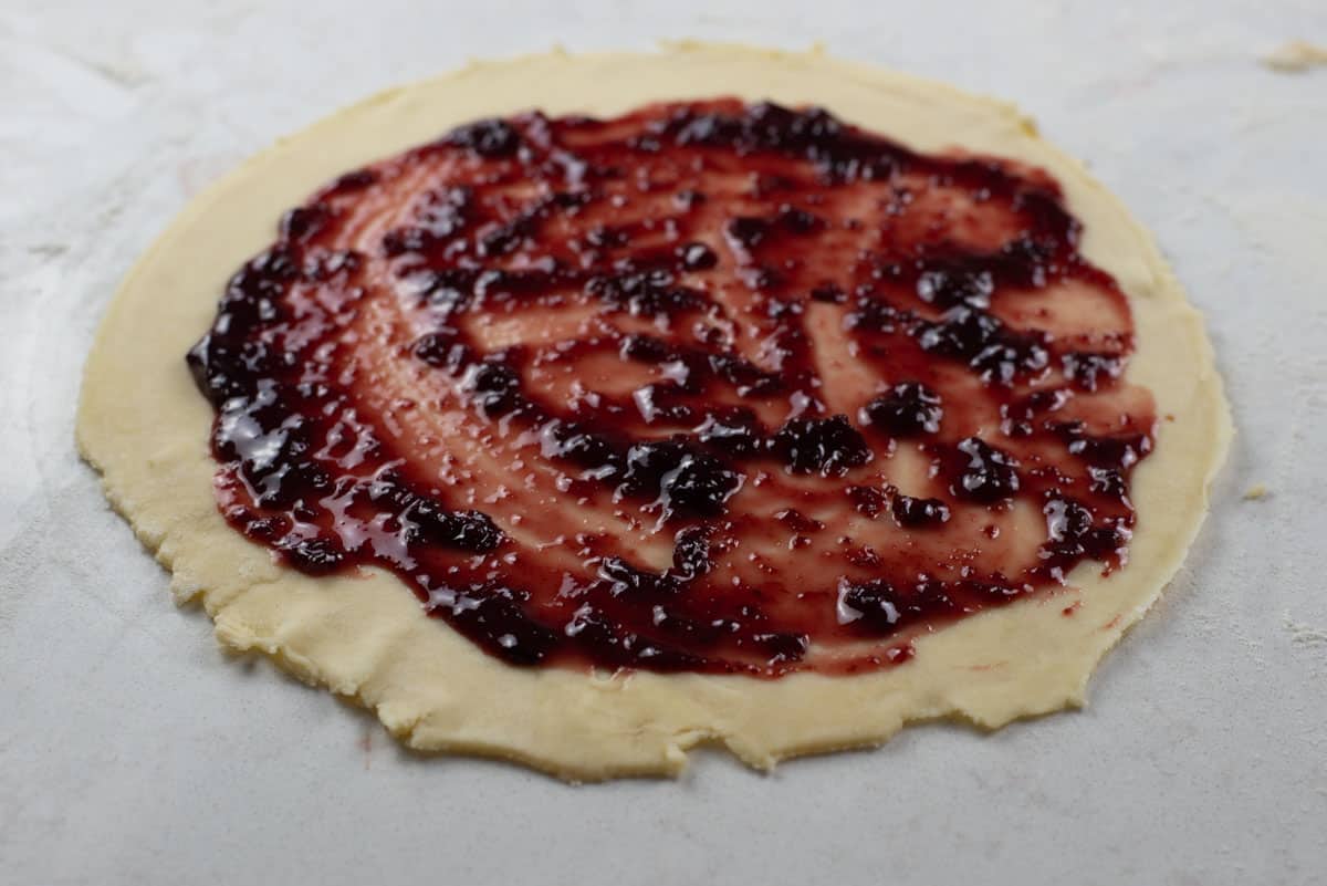 Spread cherry jam onto rolled out rugelach dough.