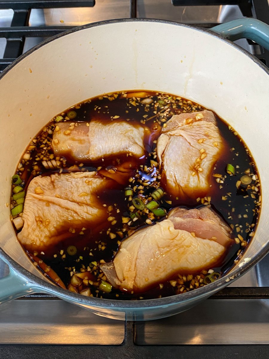 Add skin on and bone in chicken pieces to the shoyu sauce.