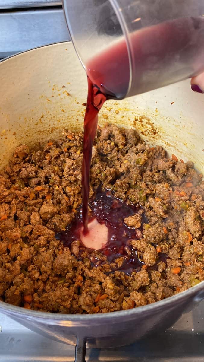 Pour red wine into the meat mixture and let wine reduce.