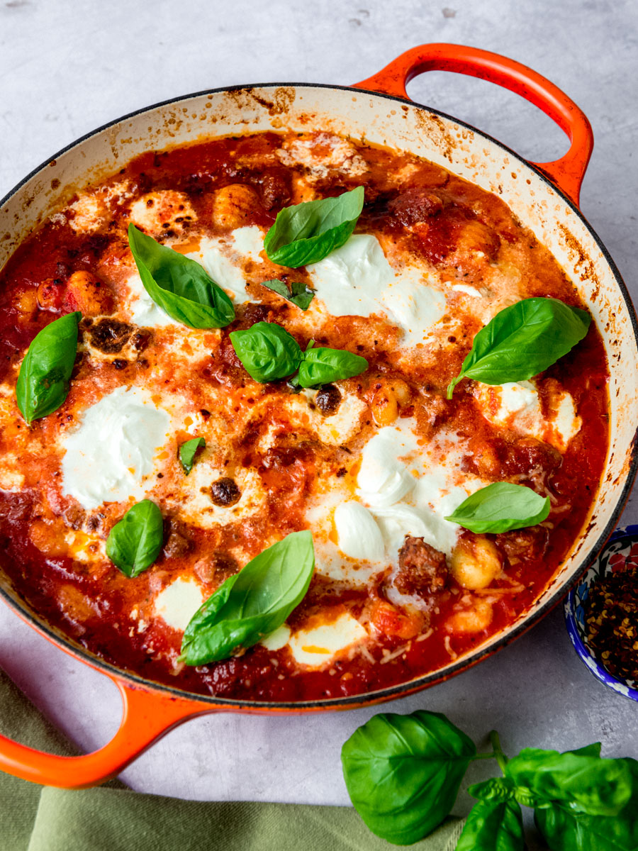 Decadent gnocchi al forno also called baked gnocchi, s garnished with fresh basil leaves and chunks of burrata cheese in a simple tomato sauce.