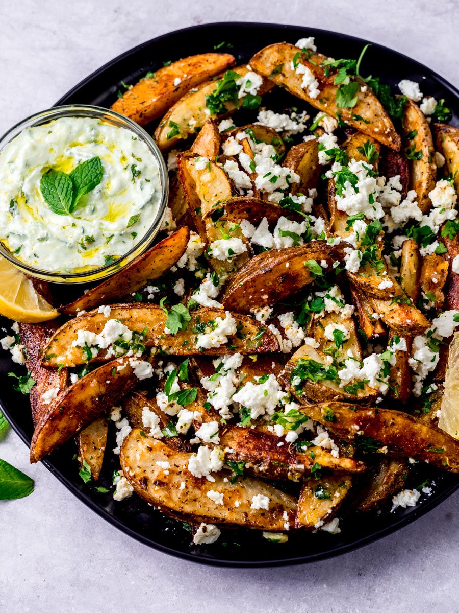 Greek feta fries are roasted until golden brown and garnished with fresh herbs and a lemon olive oil sauce with tzatziki on the side.