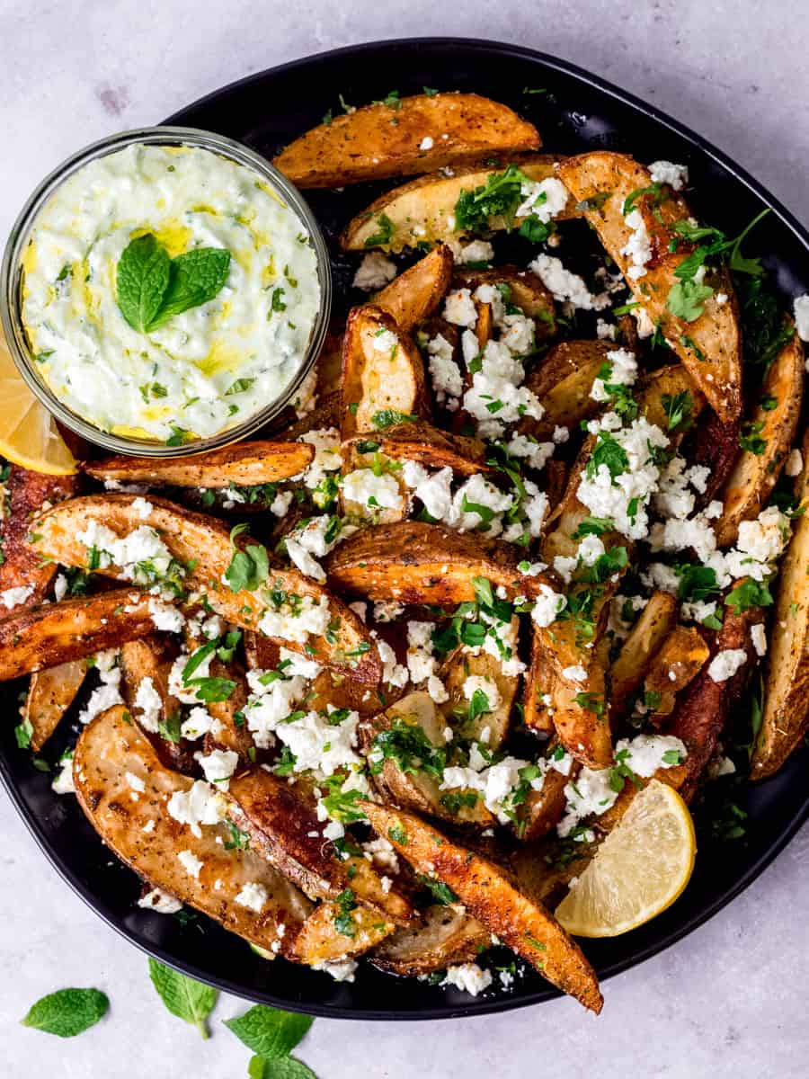 Greek fries with thick potato wedges, crumbled feta cheese herbs and lemon and served with tzatziki sauce on the side.