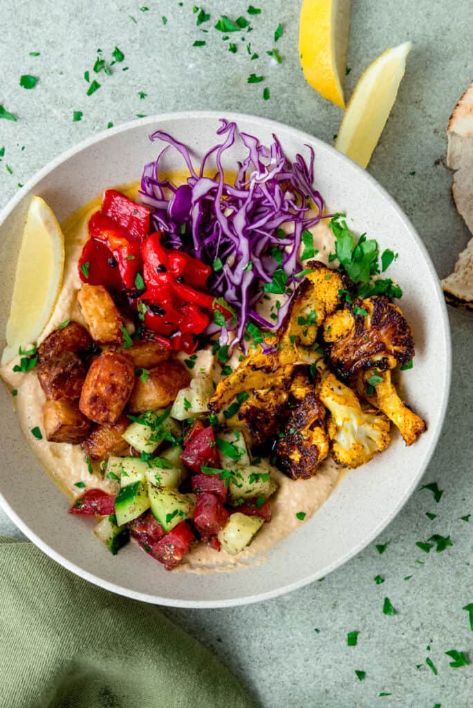 Vegetarian hummus bowls with chopped salad, roasted cauliflower and cubes of fried halloumi.