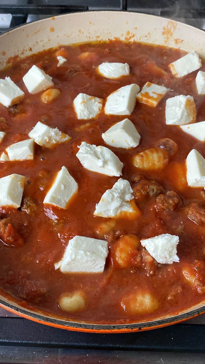 Add cubes of mozzarella cheese to the gnocchi, sausage and tomato sauce mixture,
