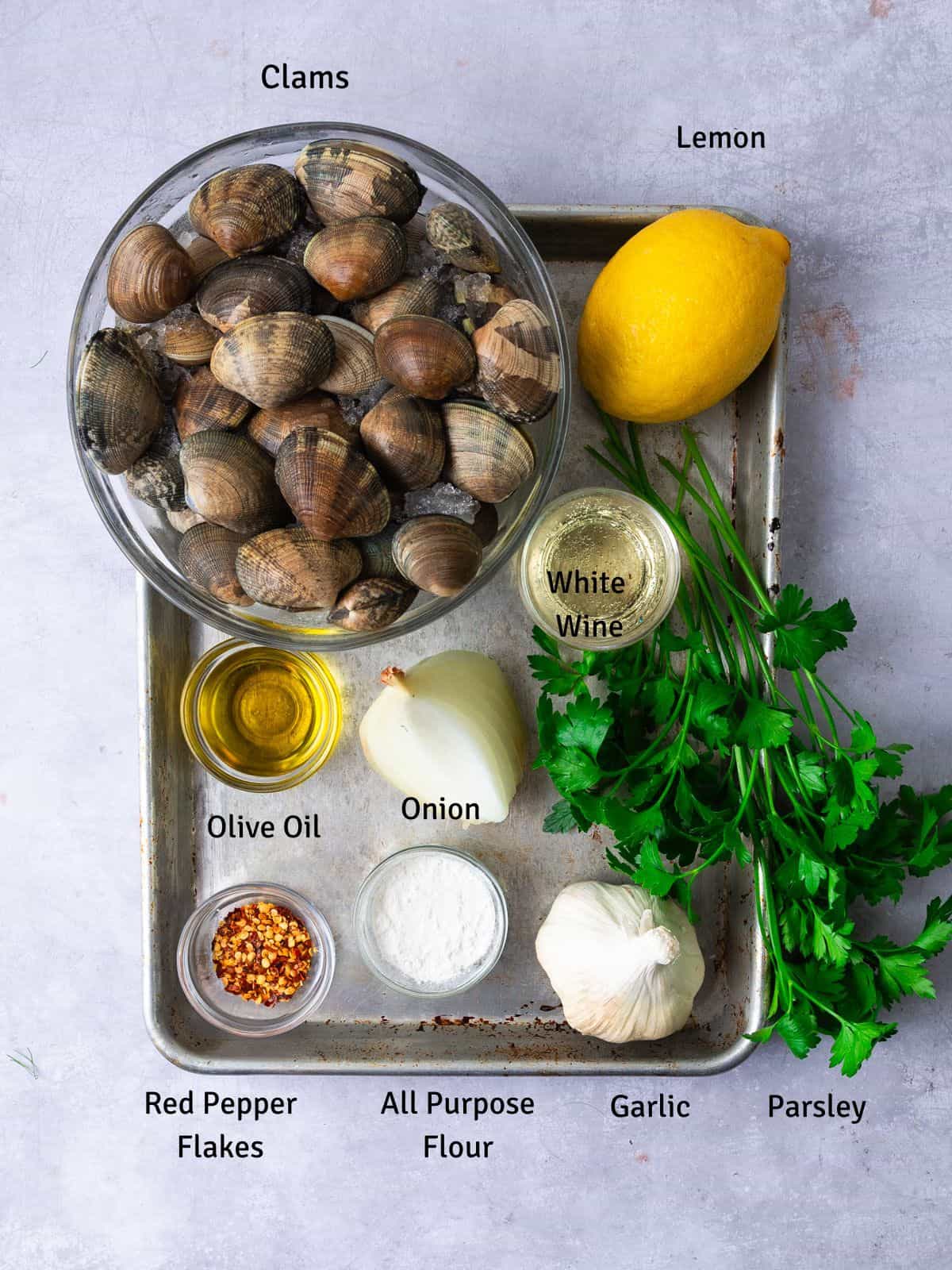 Ingredients for almejas en salsa verde, aka Spanish steamed clams in green sauce with fresh lemon, white wine and garlic.