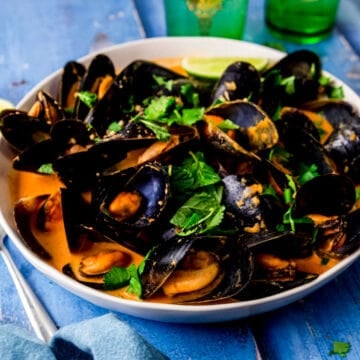 Coconut curry mussels in a creamy coconut broth with fresh lime as garnish.