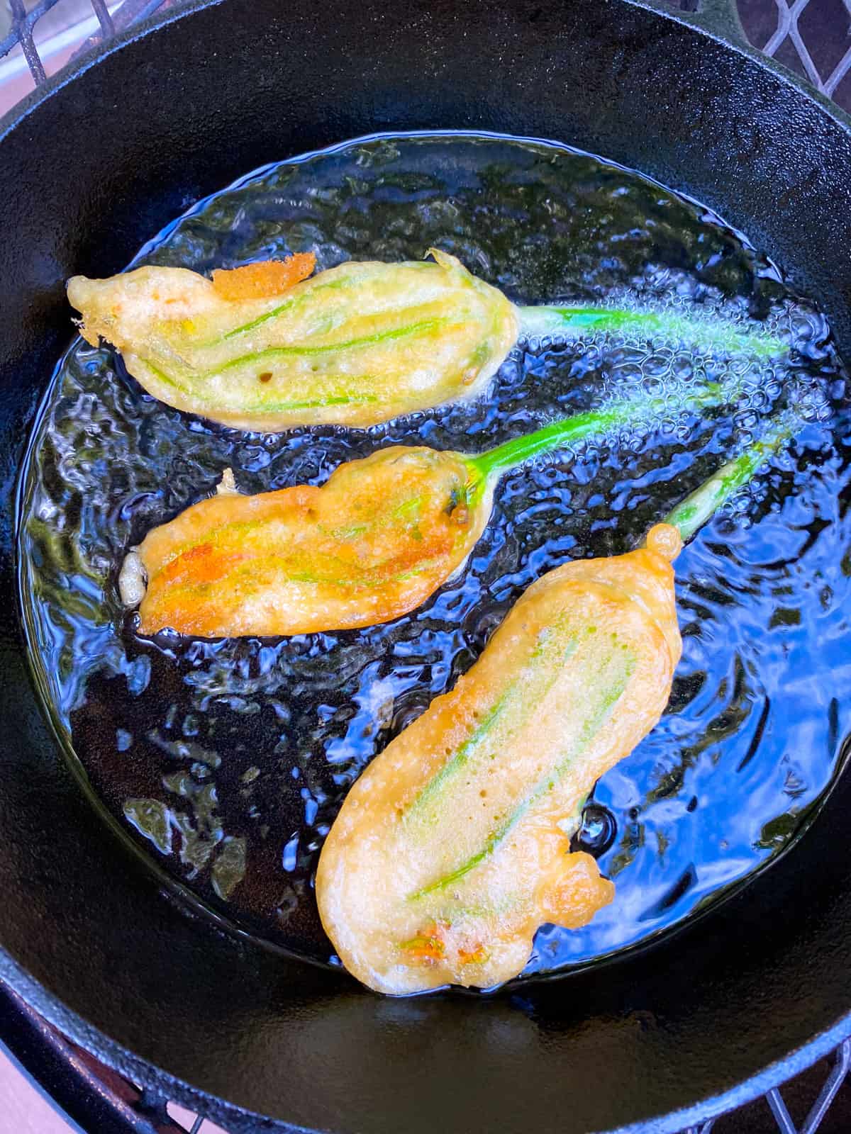 Fry the zucchini flowers in hot oil until golden brown.