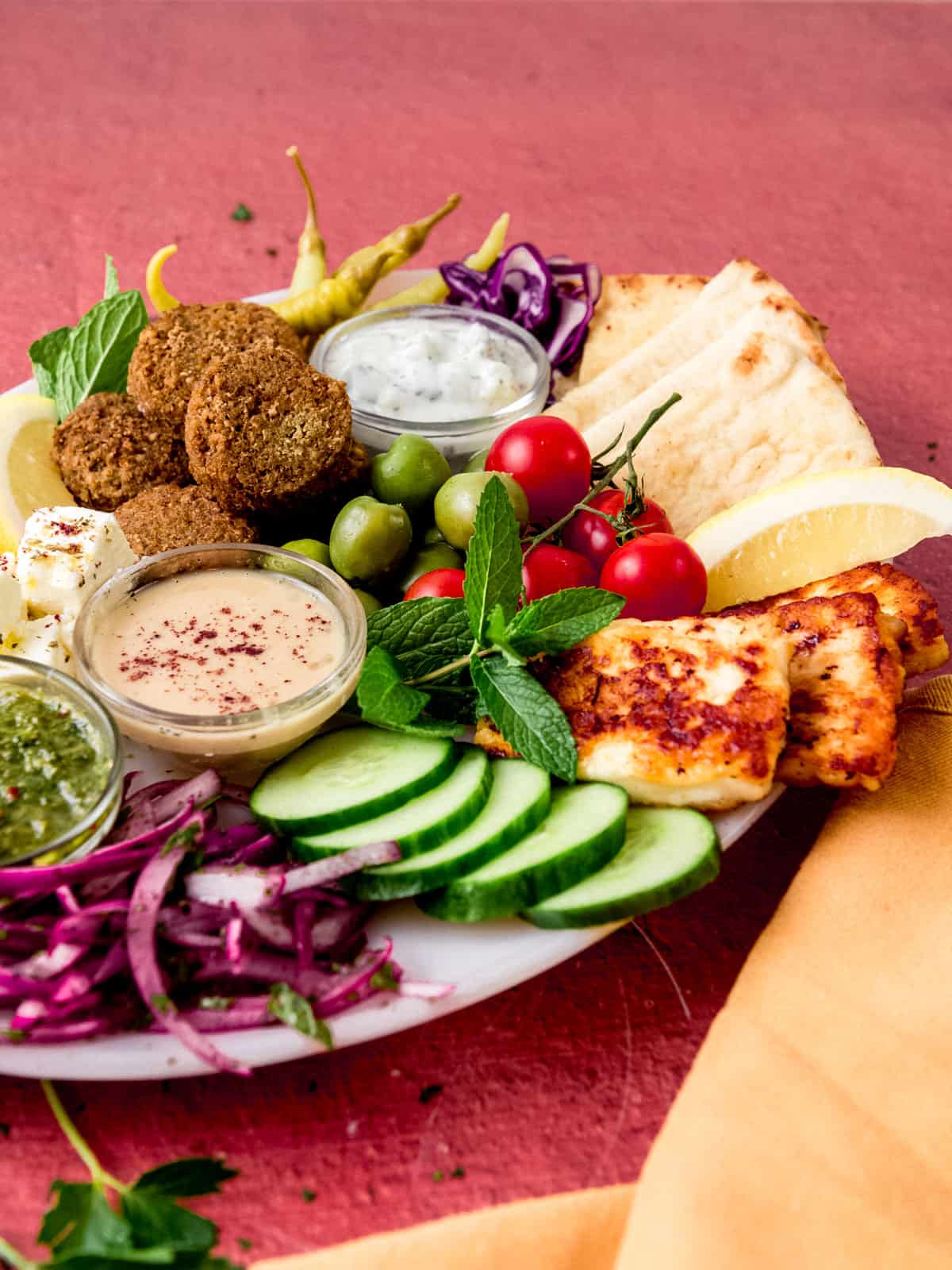 Mediterranean falafel platter with fried halloumi cheese, fresh vegetables, pita bread and tahini sauce.