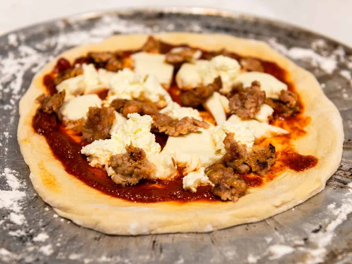 Add cooked crumbled Italian sausage to the cheese pizza.