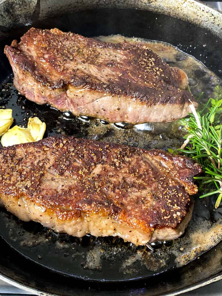 Once you turn the seared steaks over, add herbs, garlic and another tablespoon of butter.