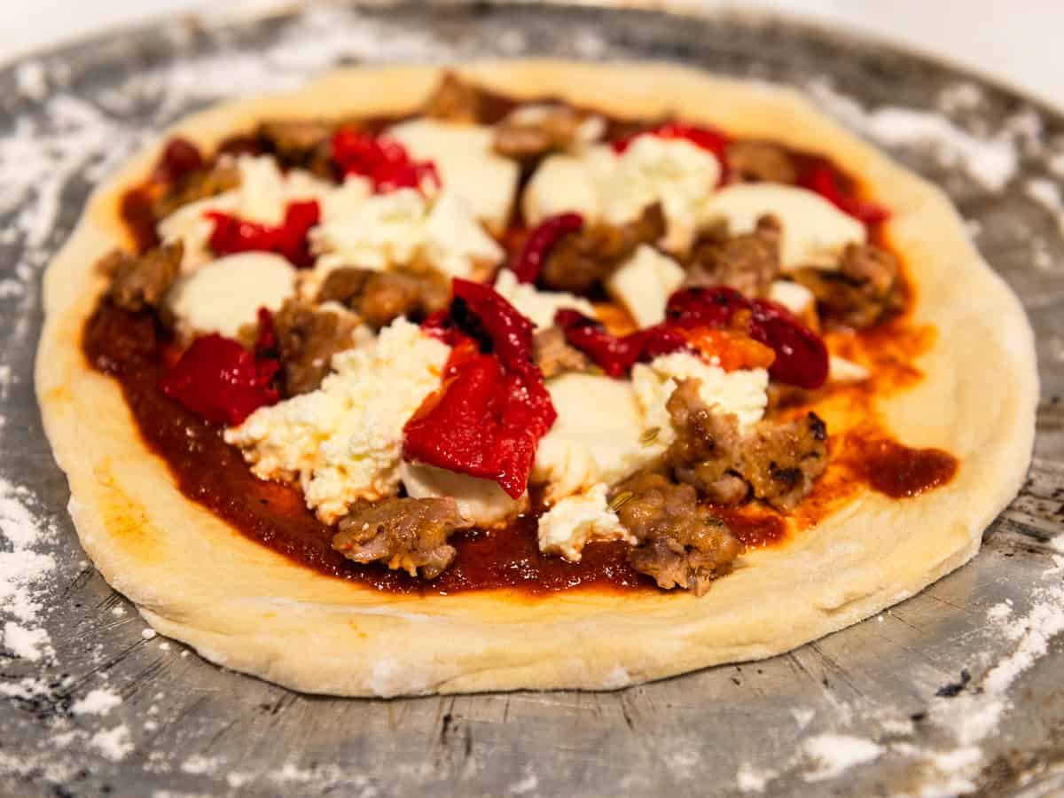 Add roasted red peppers to thee sausage and cheese pizza.