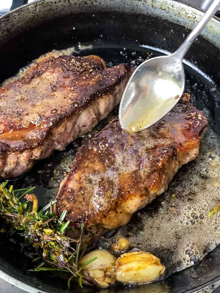 Baste the seared steaks with a garlic and herb infused butter.