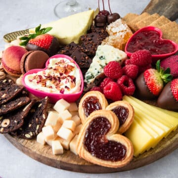 Medium sized dessert cheese board with cheese, macarons and jams.