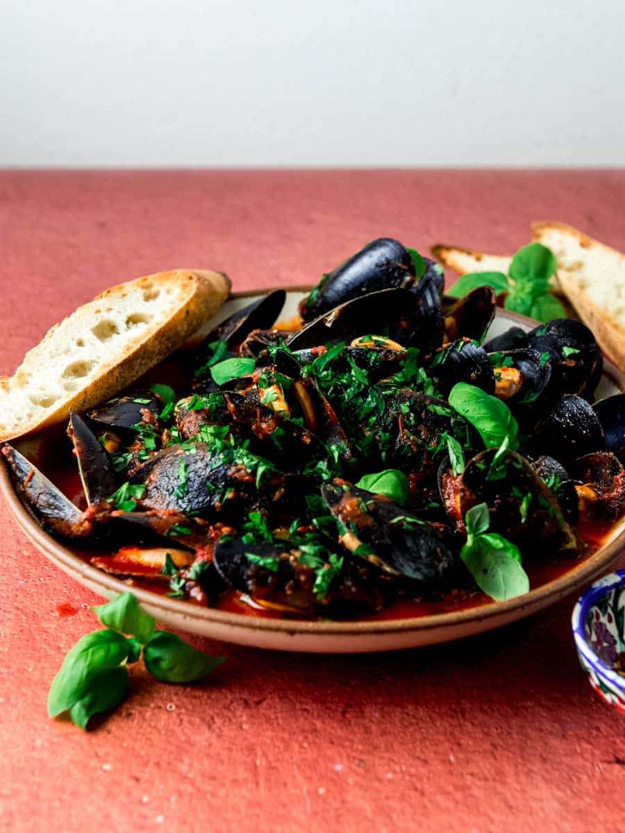 Mussels steamed in marinara sauce and garnished with fresh basil leaves.