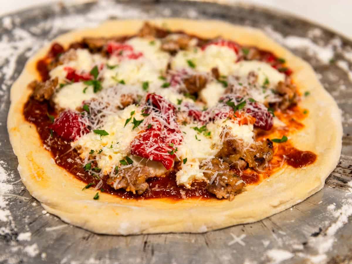 Top the sausage pizza with a grating of parmesan cheese.