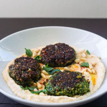 Green falafel with herbs is perfectly fried and served on top of hummus.