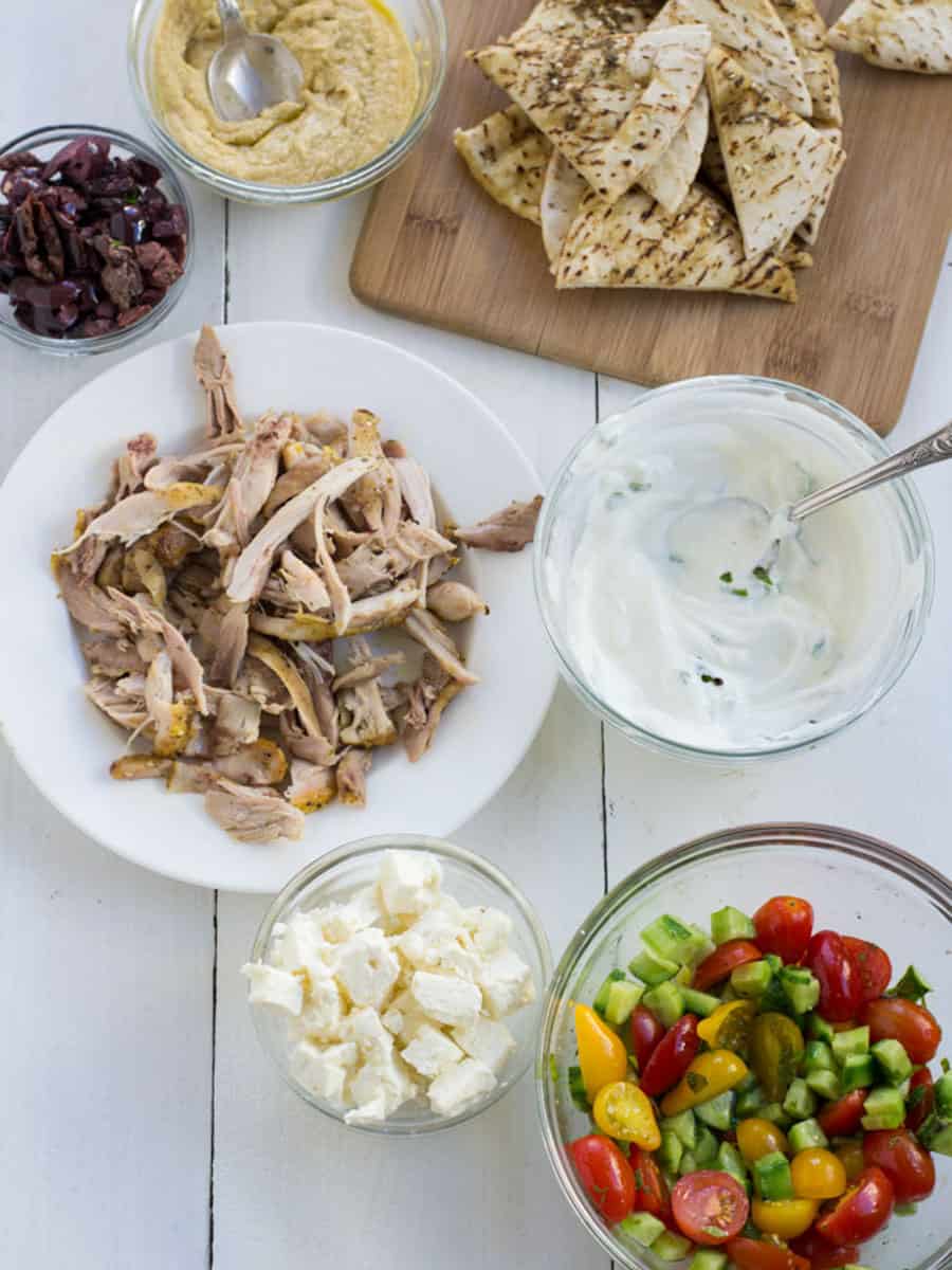 Ingredients for Greek nachos, including hummus, pita bread, yogurt and olives.