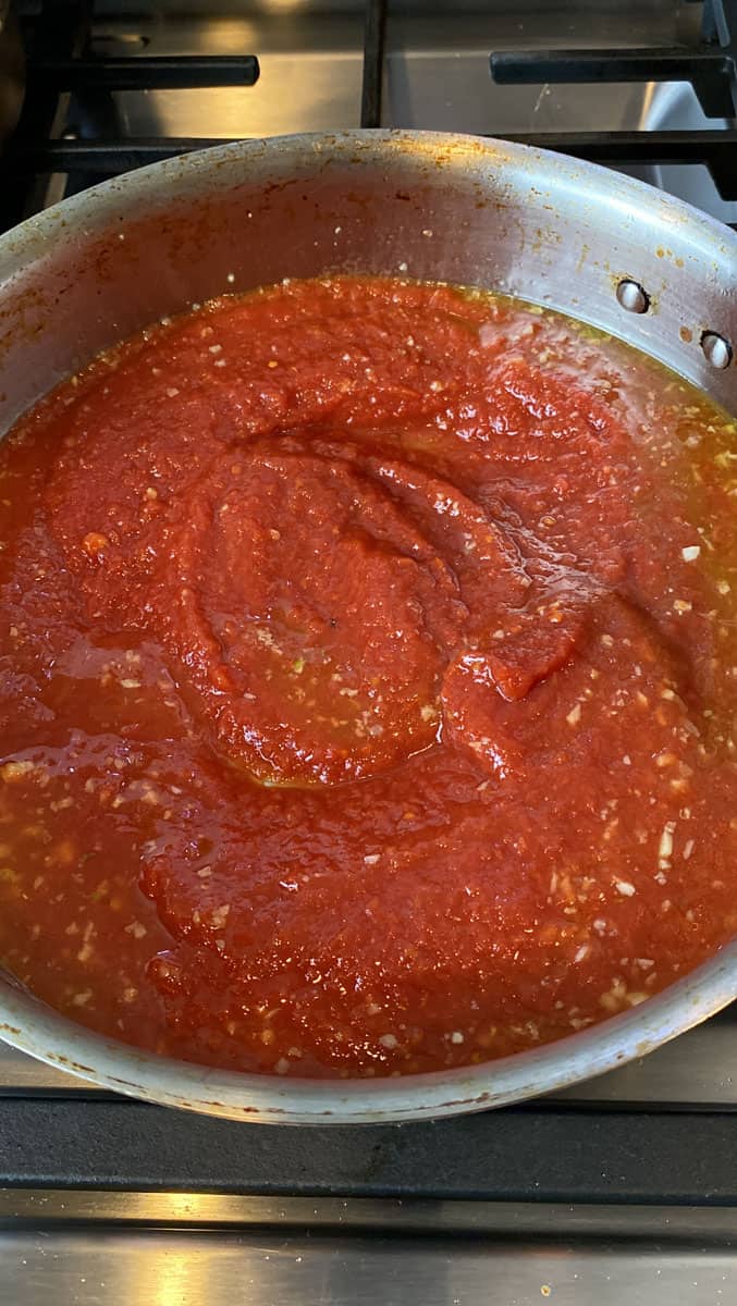 Add crushed tomatoes to the garlic and olive oil stir together.