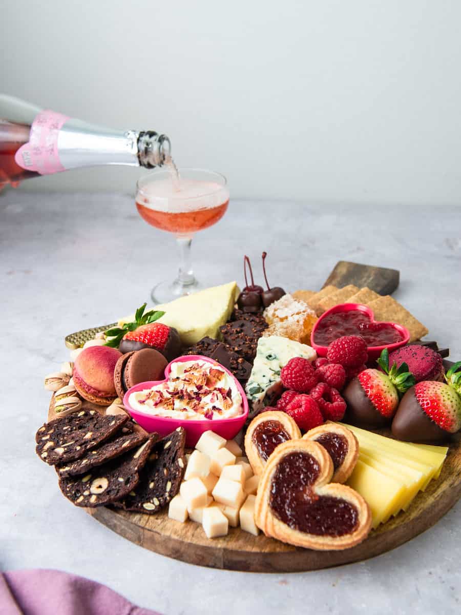 Dessert charcuterie board with different cheeses, cookies, chocolate and served with sparkling rosé.