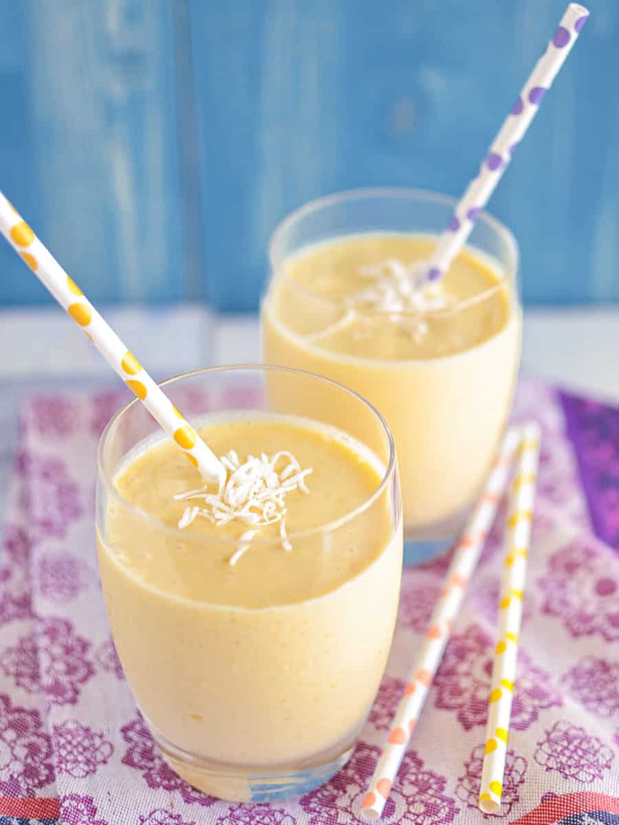 Smooth and creamy mango lassi with cardamom and topped with shredded coconut.
