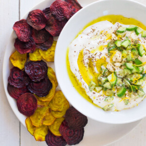 Red and yellow oven baked beet chips are served alongside a creamy lemon labneh dip.
