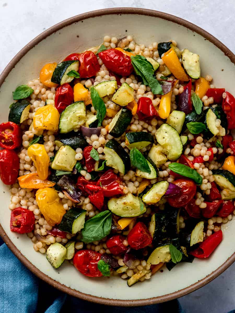 Israeli couscous with colorful roasted vegetables, including roasted zucchini, cherry tomatoes and bell peppers.