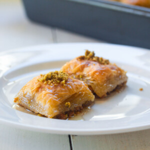 Plate of homemade pistachio baklava doused in a honey syrup.