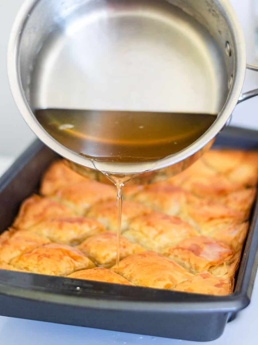 Once the homemade baklava is cooked and golden brown, pour the simple syrup all over the top to soak in.