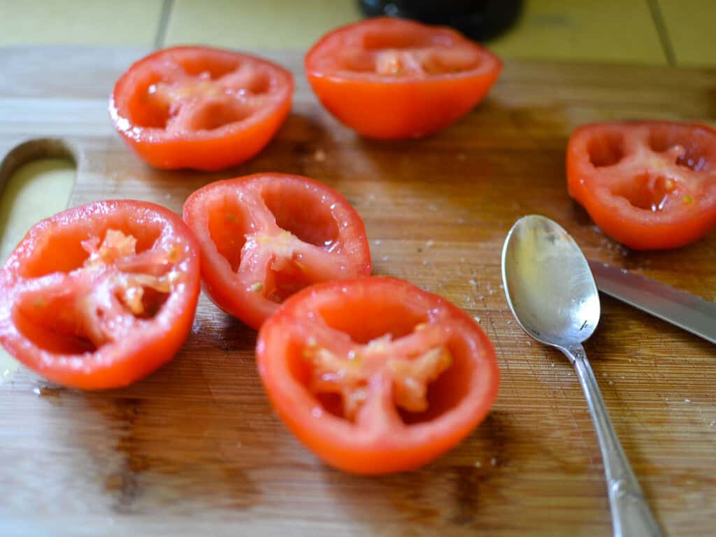 Cut the tomatoes in half and use a spoon to scoop out the seeds and some of the flesh.