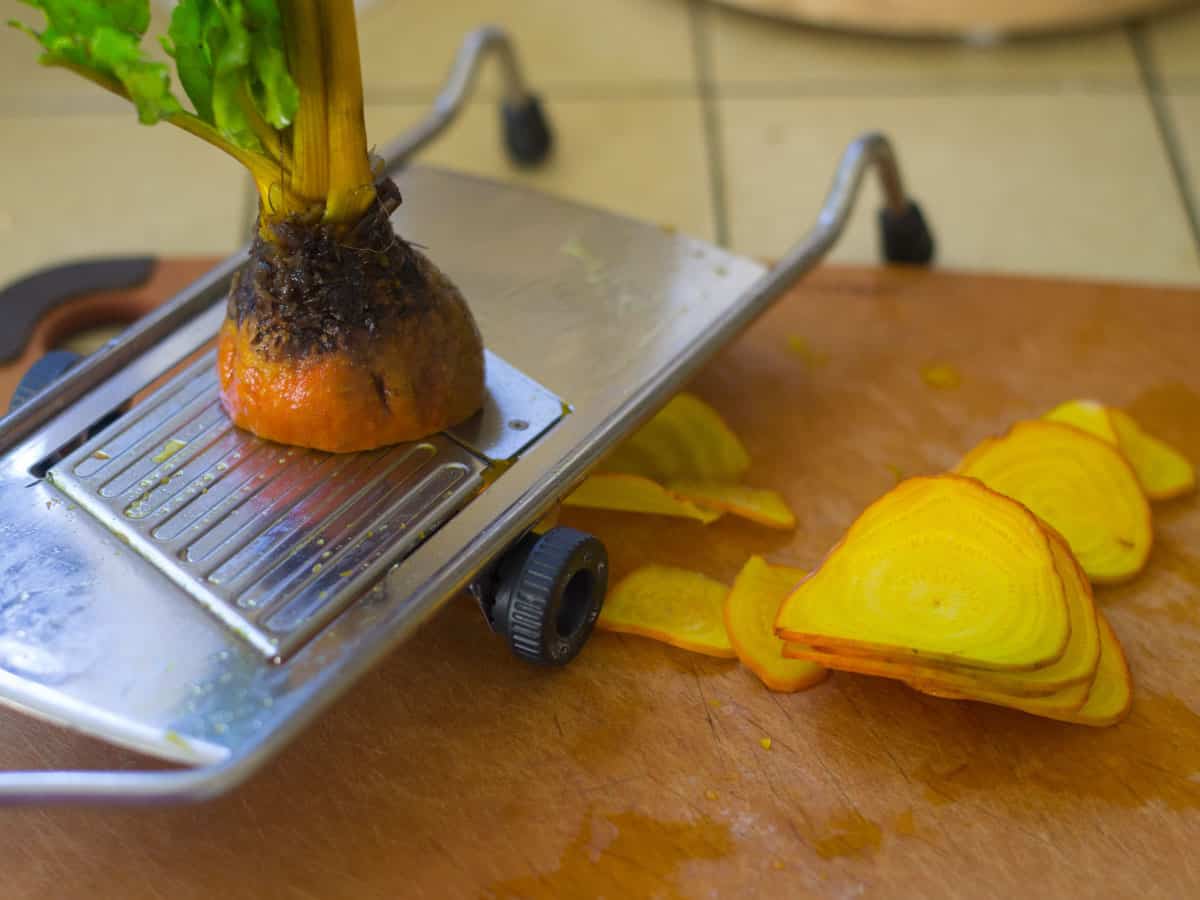 Use a mandoline to slice fresh beets into thin slices for baking.