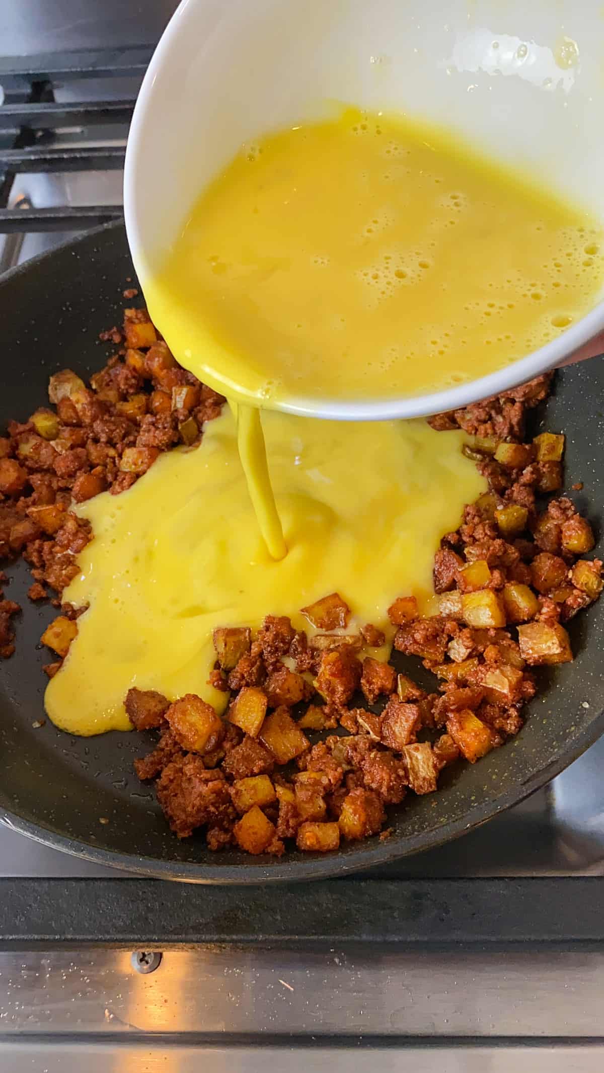 Pour the whisked eggs into the chorizo and potato mixture.