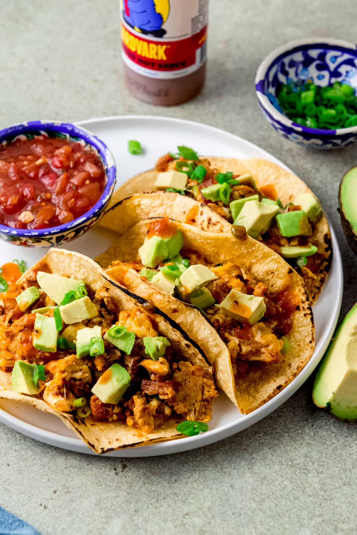 Breakfast tacos with chorizo and potatoes and topped with hot sauce and avocado.