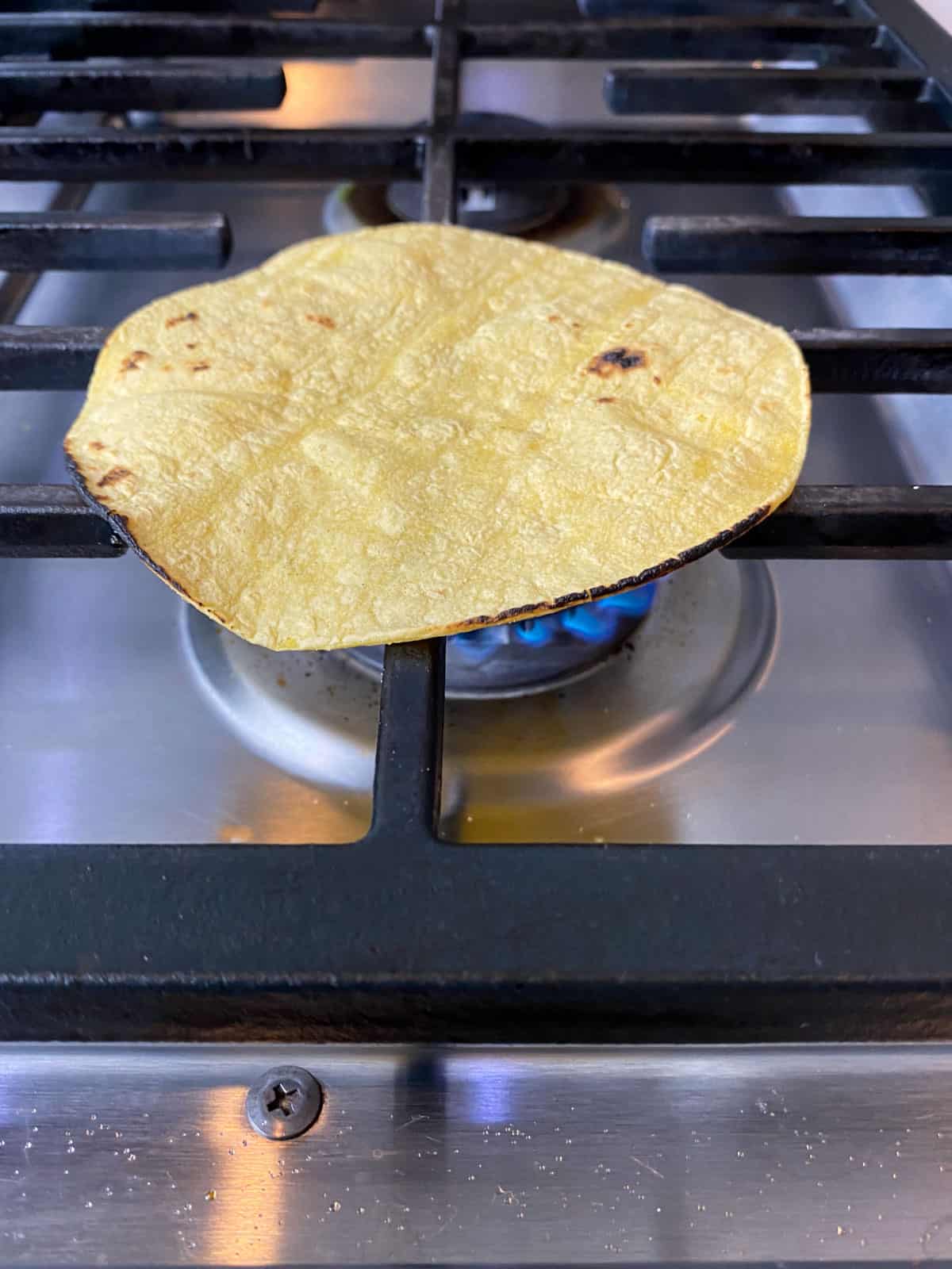 Char the corn tortilla directly on the stove top until the edges are lightly charred.