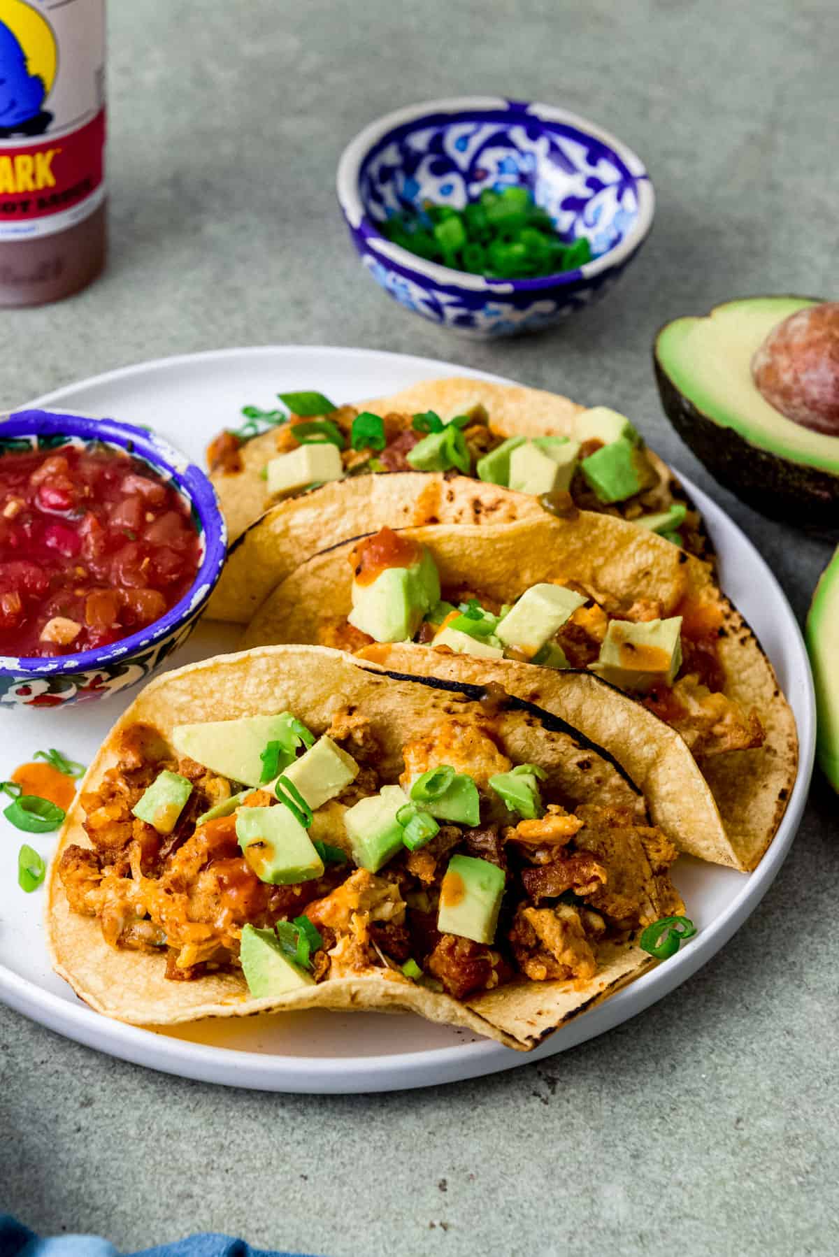 Chorizo breakfast tacos with eggs and potatoes and topped with avocado and hot sauce.