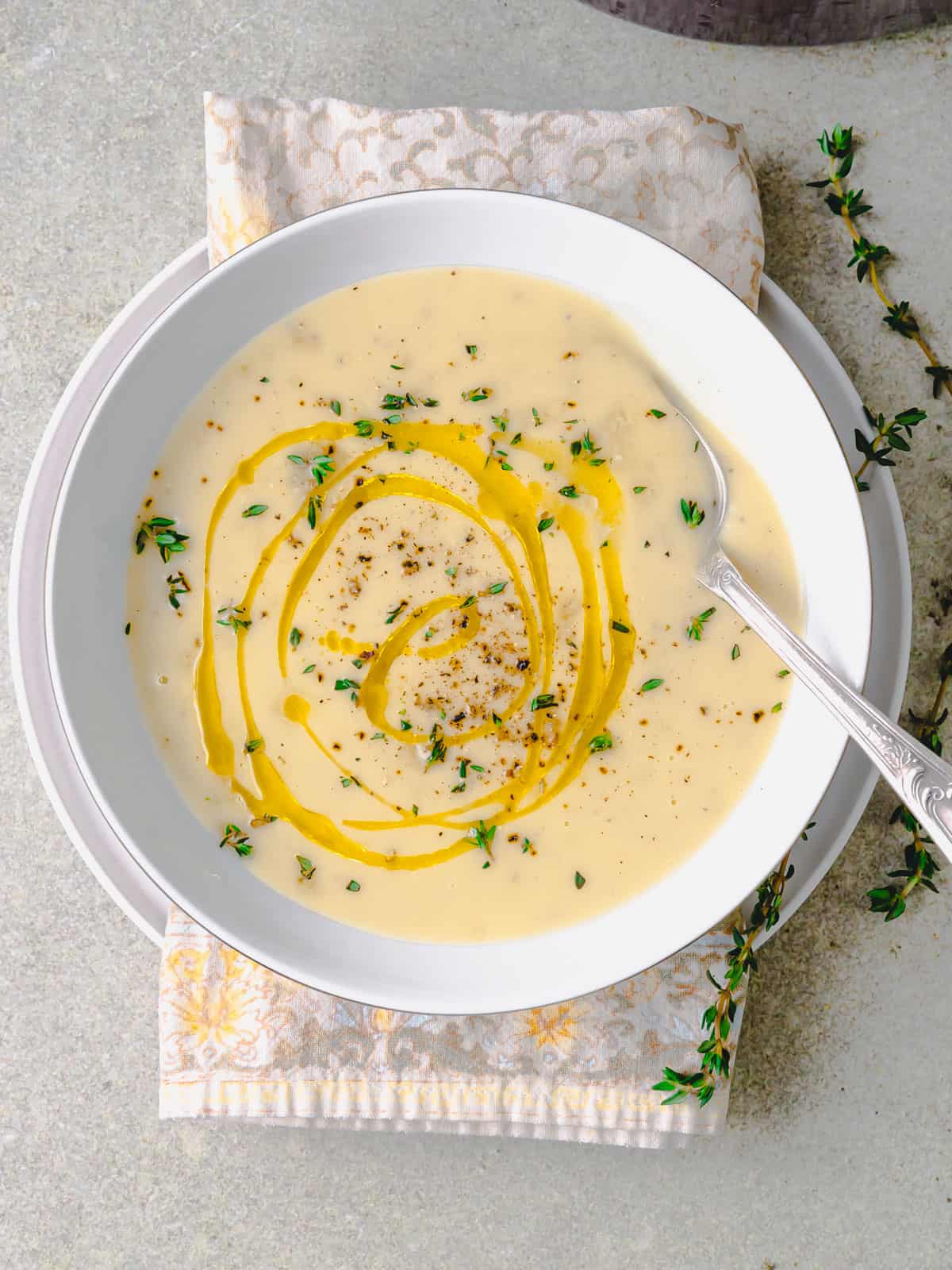 Creamy potato leek soup topped with fresh thyme and a drizzle of olive oil.