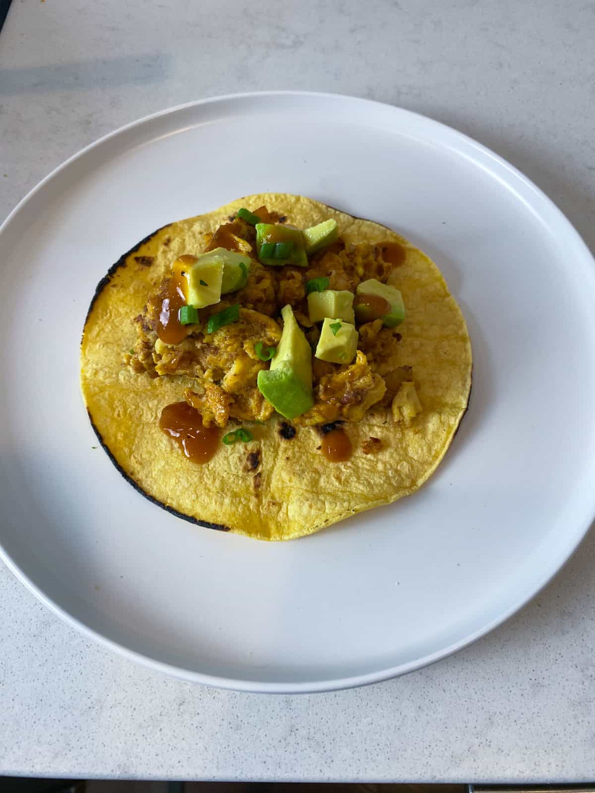 Garnish the breakfast taco with cubed avocado and hot sauce.
