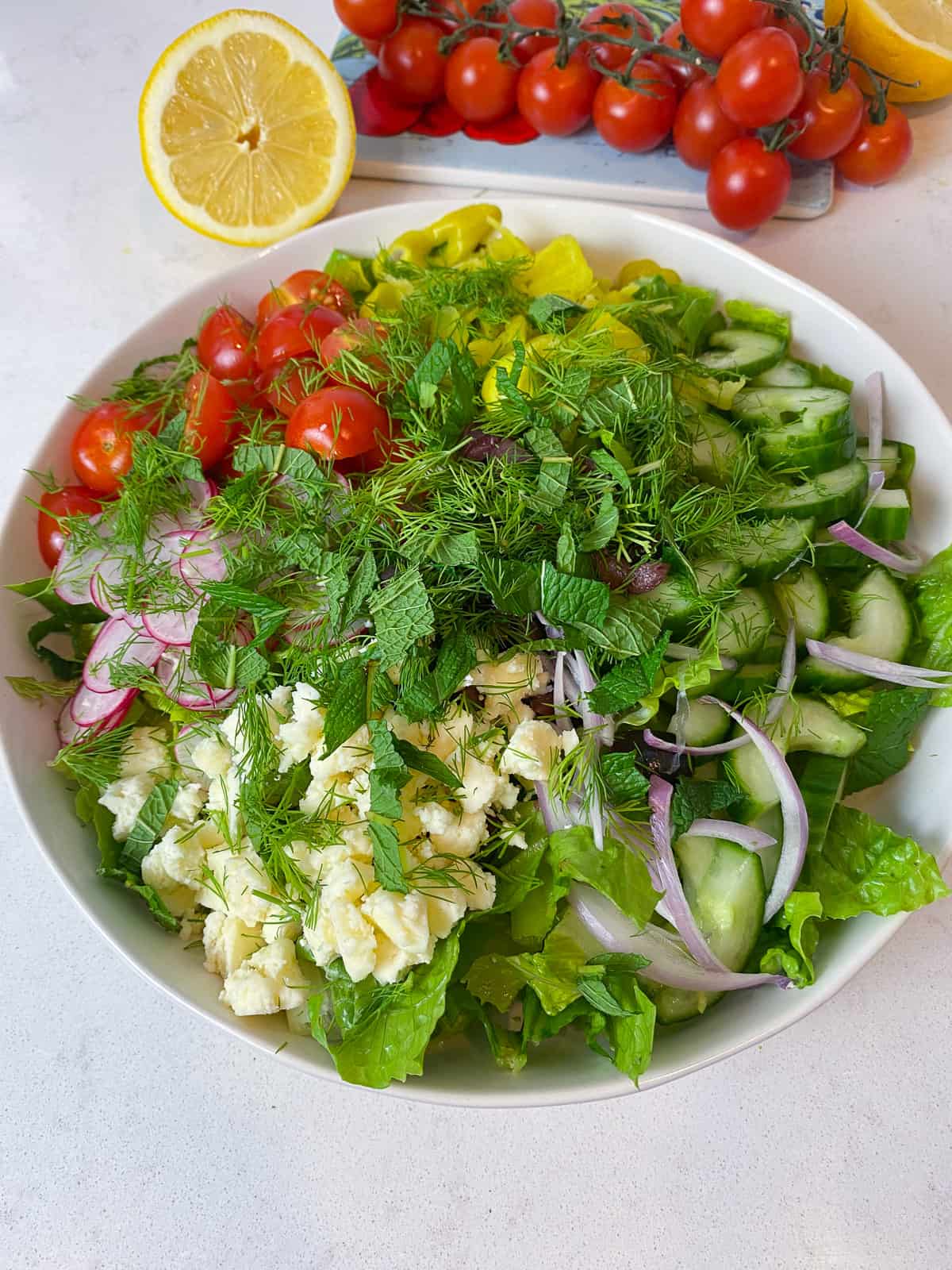 Add the fresh herbs on top of the Greek salad.