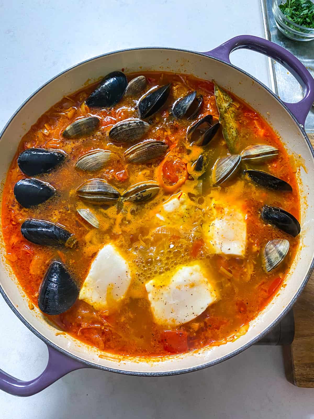 Add the cleaned mussels and clams to the simmering seafood stew and cook for 2-3 minutes before adding the other seafood.