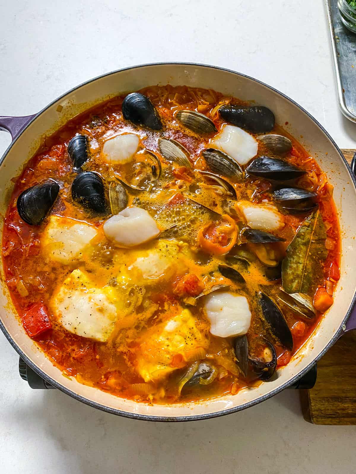 Add the scallops to the simmering bouillabaisse (French seafood stew).