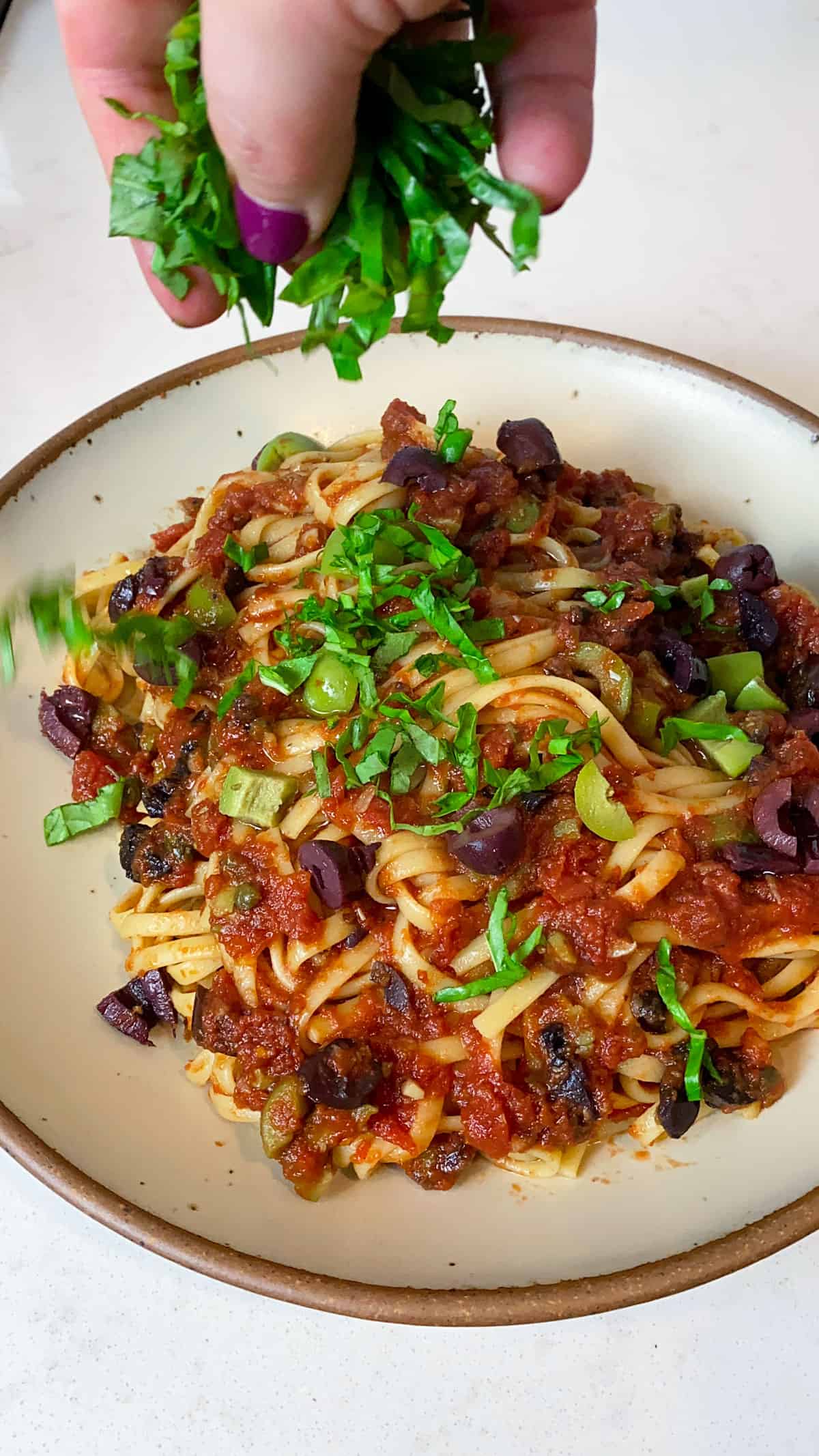 Garnish the puttanesca pasta with fresh basil.